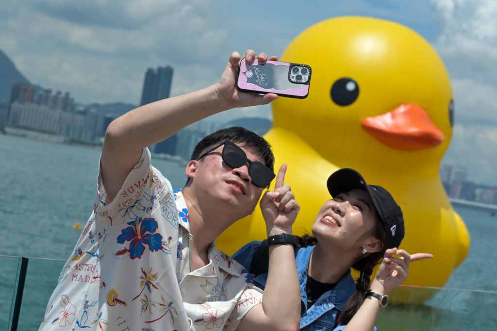 Visitors take photos with two giant rubber ducks floating in Hong Kong's Victoria Harbor on June 10, 2023. /CFP