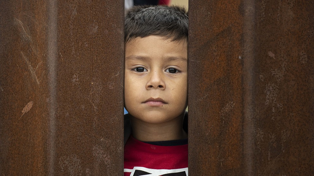 A young Asylum seeker peers through the border wall between the San Diego, California border and Mexico border, U.S., May 12, 2023. /CFP