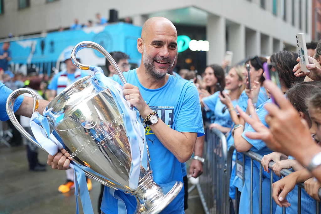 Pep Guardiola, manager of Manchester City, holds the UEFA Champions League title trophy during the parade in Manchester, England, June 12, 2023. /CFP