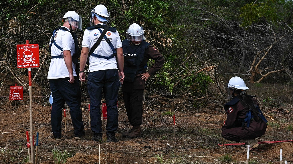 Deminers look at a mine in the ground during a technical training session on demining technologies in Battambang Province, Cambodia, January 19, 2023. /CFP