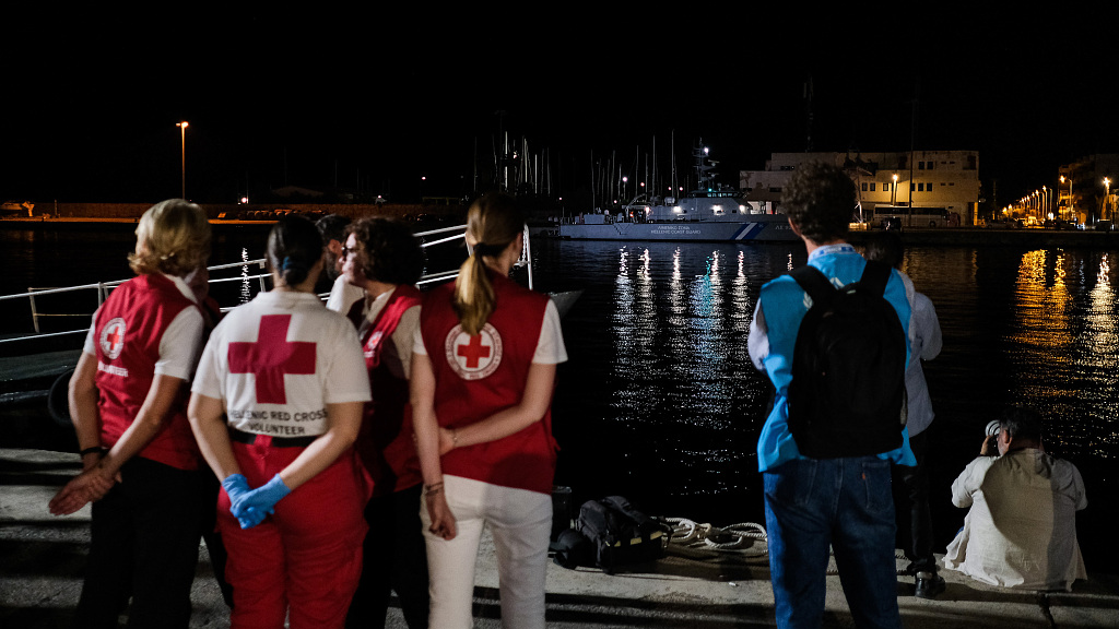 Members of the Red Cross and UNHCR wait outside of a hangar where more than 100 migrants have been temporarily housed in Kalamata, Greece, June 14, 2023. /CFP 