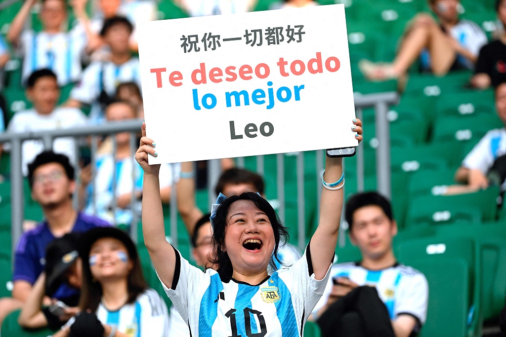 A Lionel Messi fan holds a board saying 