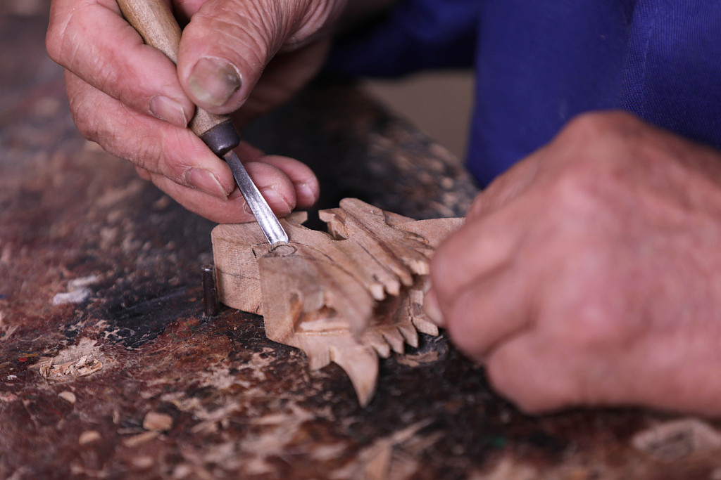 The photo taken on May 7, 2021 shows carpenter Zhou Chengyun making small wooden dragon boats ahead of the upcoming Dragon Boat Festival. /CFP