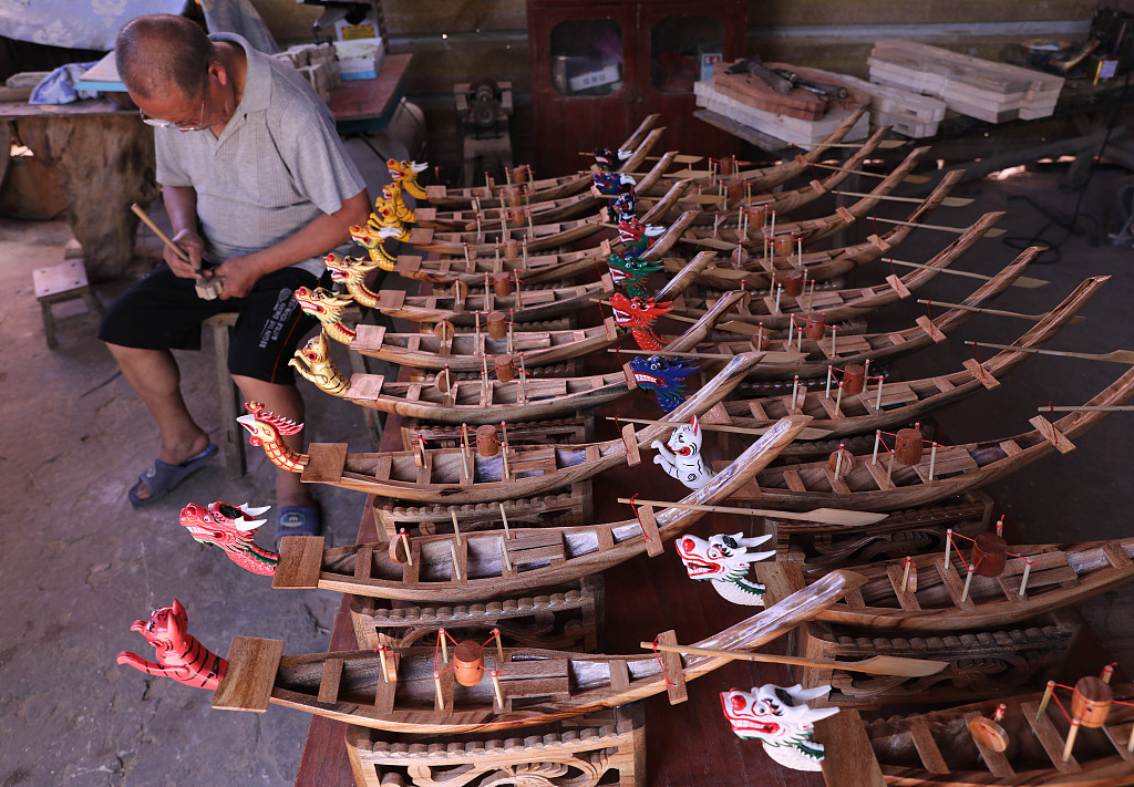 The photo taken on June 13, 2021 shows carpenter Zhou Chengyun making small wooden dragon boats ahead of the upcoming Dragon Boat Festival. /CFP