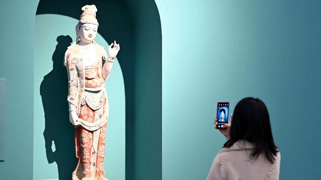 A visitor takes photos of a 3D print of a Mogao Grottoes colored sculpture during an exhibition in Lanzhou, capital city of northwest China's Gansu Province, March 3, 2023. /CFP
