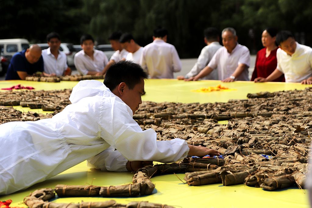 A man arranges dumplings into the pattern of a flying dragon at Laojun Mountain, Henan Province, June 6, 2019. /CFP