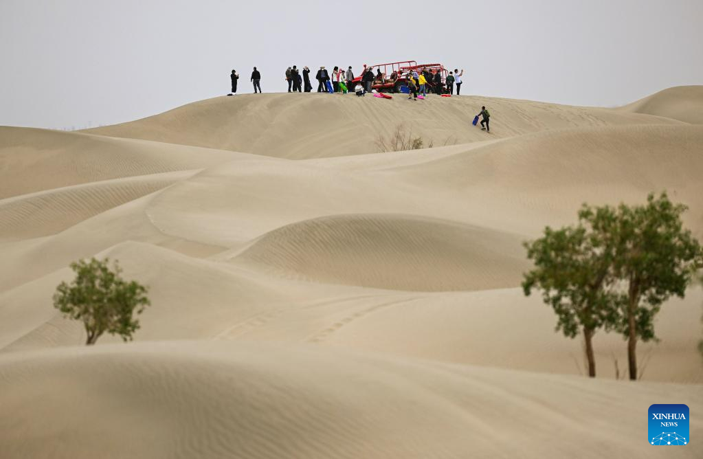 Tourists have fun at a desert in Makit County, northwest China's Xinjiang Uygur Autonomous Region, May 26, 2023. /Xinhua