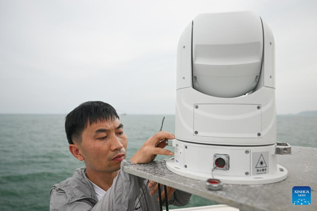 An employee installs a high-definition optoelectronic device before conducting open-sea testing of the low-Earth orbit broadband communication test constellation at the 