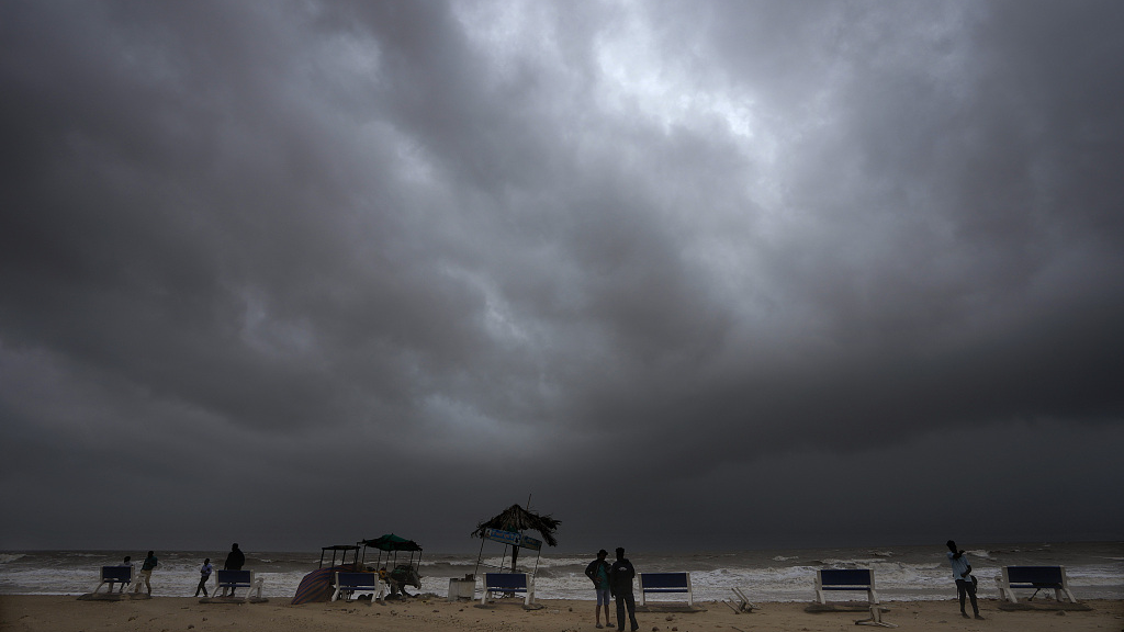 Rain clouds fill the sky as media persons stand at a deserted beach ahead of cyclone Biparjoy's landfall at Mandvi in Kutch district of Gujarat state, India, June 15, 2023. /CFP