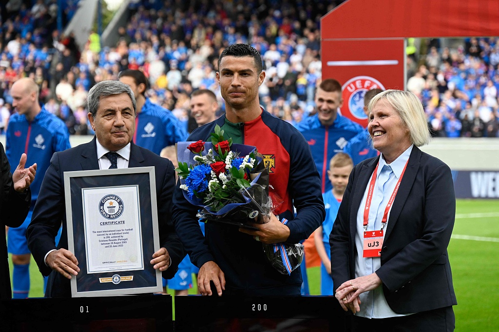 Portugal's forward Cristiano Ronaldo (C) is honored with a certificate of the Guinness World Records for becoming the first men's player to win 200 international caps at Laugardalsvollur in Reykjavik, Iceland, June 20, 2023. /CFP