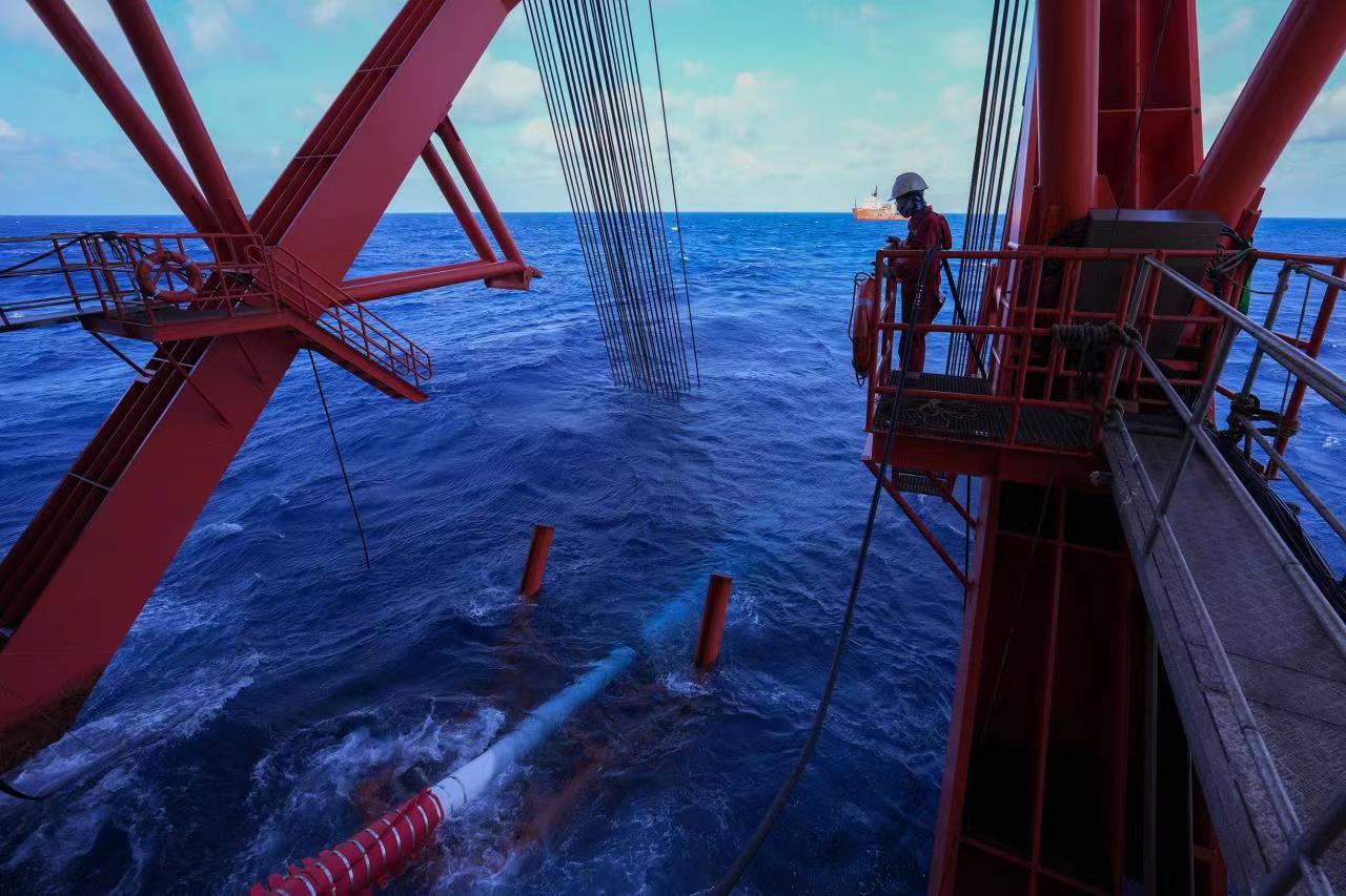Construction workers inspect pipes entering the sea. /CNOOC