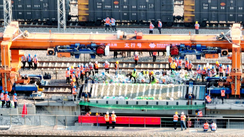 Construction workers operate the Taihang machine to replace a worn-out bridge section on the Shuohuang railway line in north China's Hebei Province, June 20, 2023. /CMG