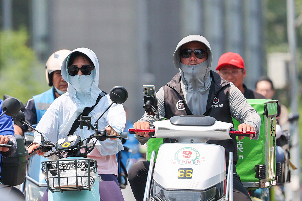 Passengers wear sun-protective clothing in Beijing, June 23, 2023. /CFP
