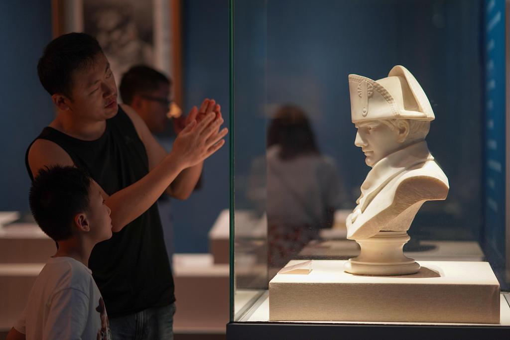 Viewers take photos of a sculpture of French emperor Napoleon Bonaparte at an exhibition titled 