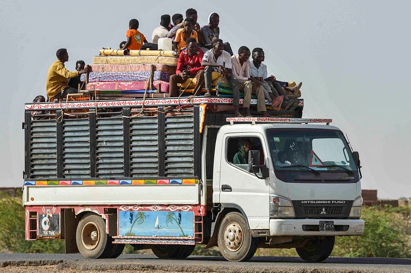 People ride with furniture and other items atop a truck moving along a road from Khartoum to Wad Madani at the locality of Kamlin, about 80 kilometres southeast of Khartoum,  June 22, 2023. /CFP