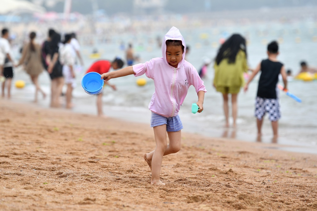 Photo taken on June 24, 2023 shows the seafront in Qingdao, Shandong Province is packed with people as locals and tourists alike flock to the beach to find respite from the high temperatures. /CFP