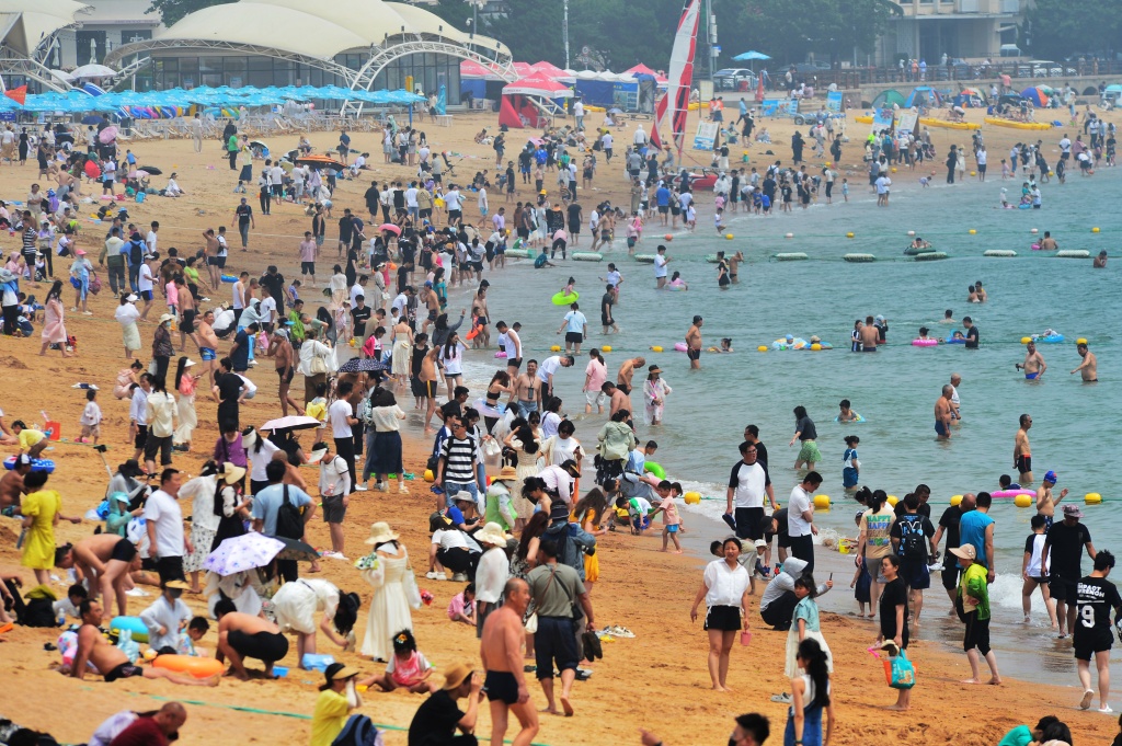 Photo taken on June 24, 2023 shows the seafront in Qingdao, Shandong Province is packed with people as locals and tourists alike flock to the beach to find respite from the high temperatures. /CFP