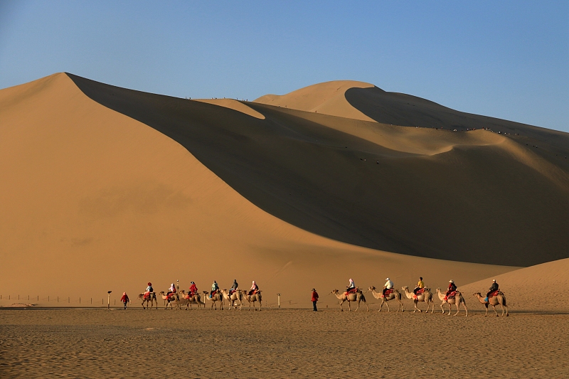 Visitors explore the desert at Mingsha Mountain Crescent Spring Scenic Area, Dunhuang, Gansu Province. /CFP