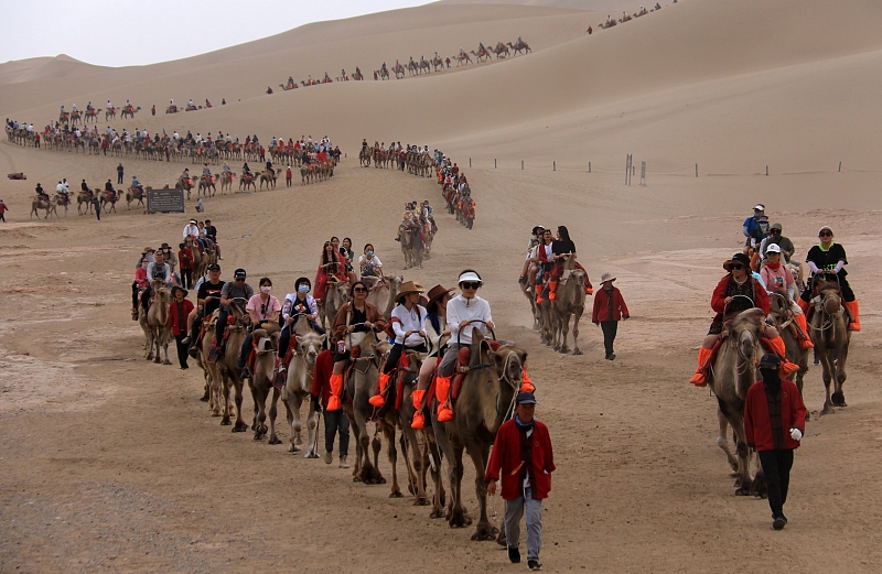 Visitors ride on camels at Mingsha Mountain Crescent Spring Scenic Area, Dunhuang, Gansu Province. /CFP