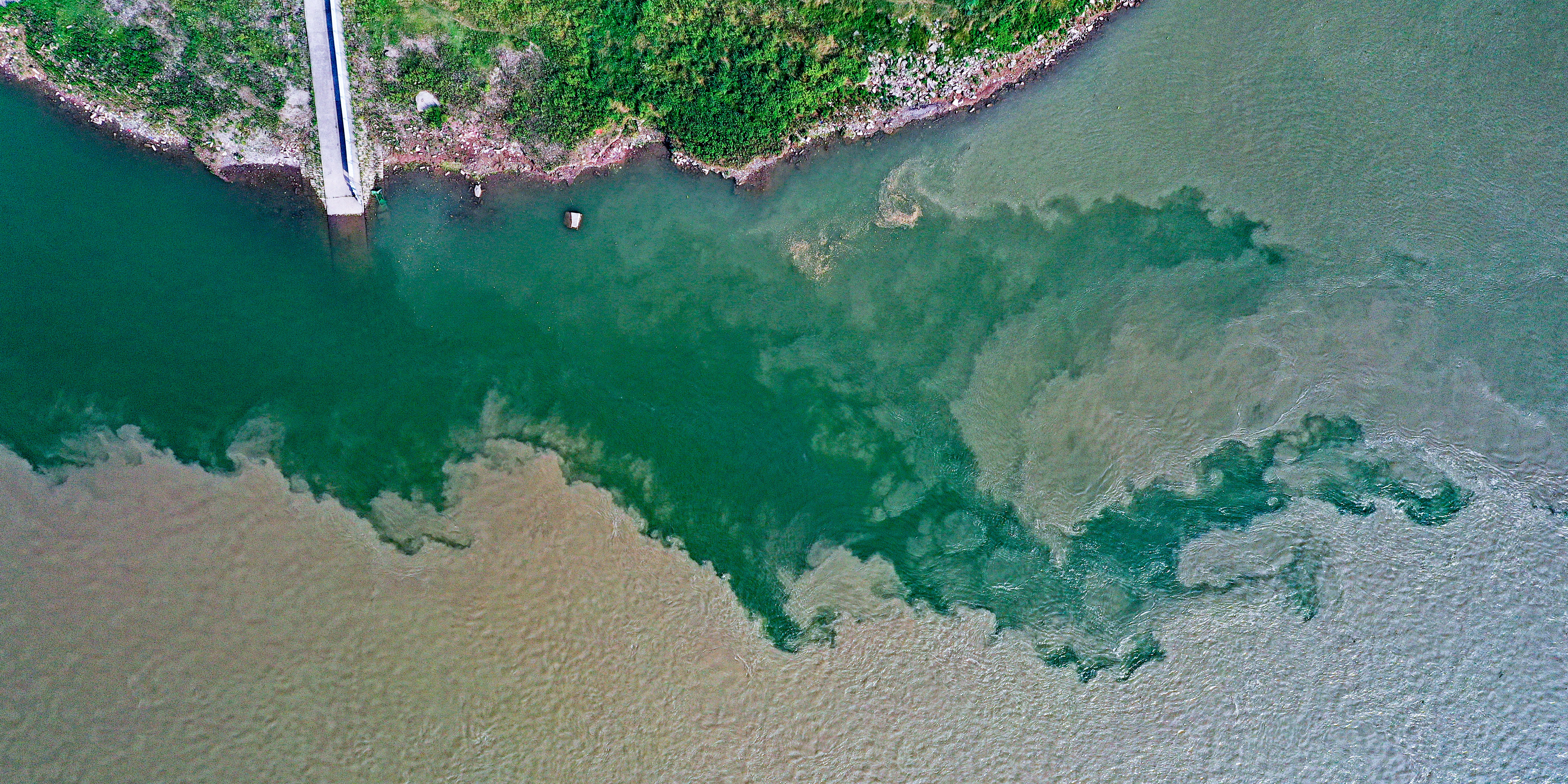 Photo taken on June 6, 2023, shows the phenomenon at the confluence of the Yangtze River and the Tuojiang River. The color differences are mainly due to their difference in debris and vegetation, causing a contrasting scene when the two bodies of water merge into one another to become a single river. /CNSPHOTO