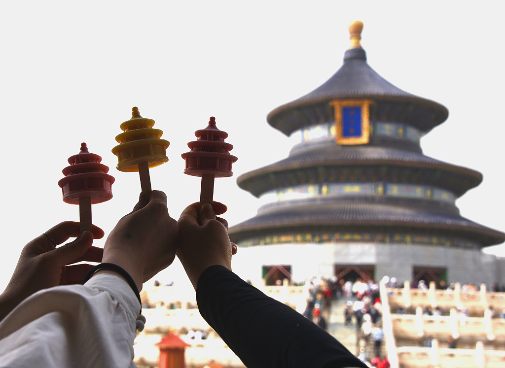 Visitors hold up ice cream cones replicating the shape of the Hall of Prayer for Good Harvests at Beijing's Temple of Heaven, a UNESCO world heritage site. /CFP