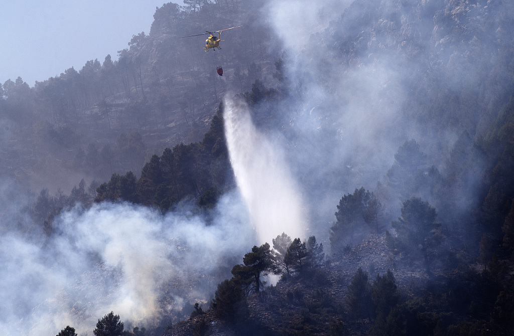 A helicopter drops water to extinguish a forest fire in Montanejos, Castellon de la Plana, Spain, March 26, 2023. /CFP