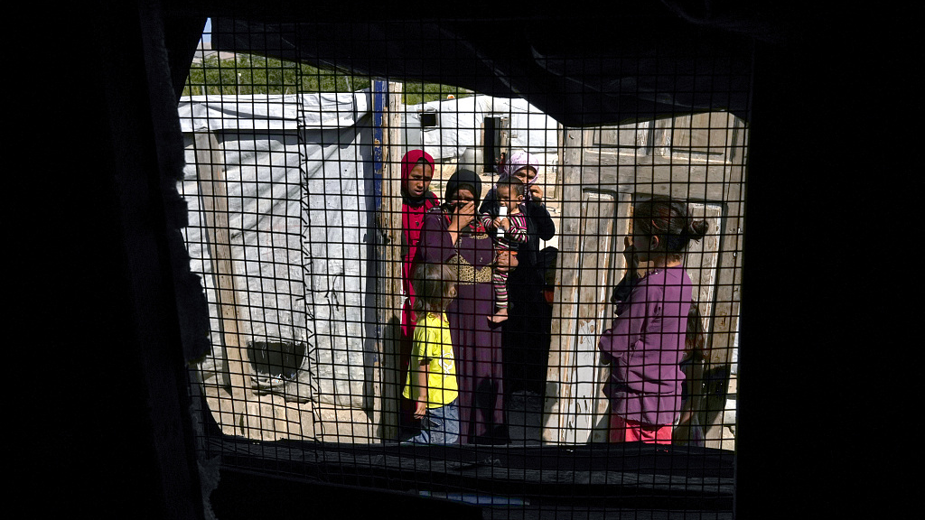 Syrian women and their children, seen through a tent window, stand at a refugee camp at the town of Bar Elias in Bekaa Valley, Lebanon, June 13, 2023. /CFP