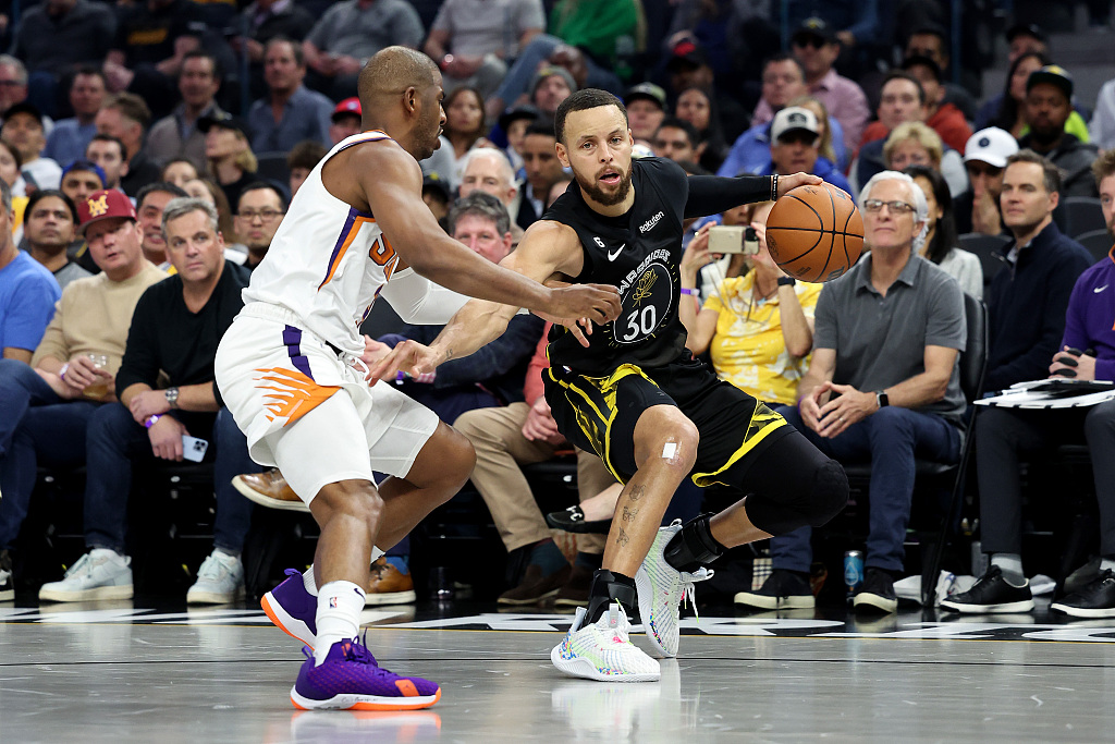 Stephen Curry (#30) of the Golden State Warriors dribbles to beat the defense of Chris Paul of the Phoenix Suns in the game at the Chase Center in San Francisco, California, March 13, 2023. /CFP