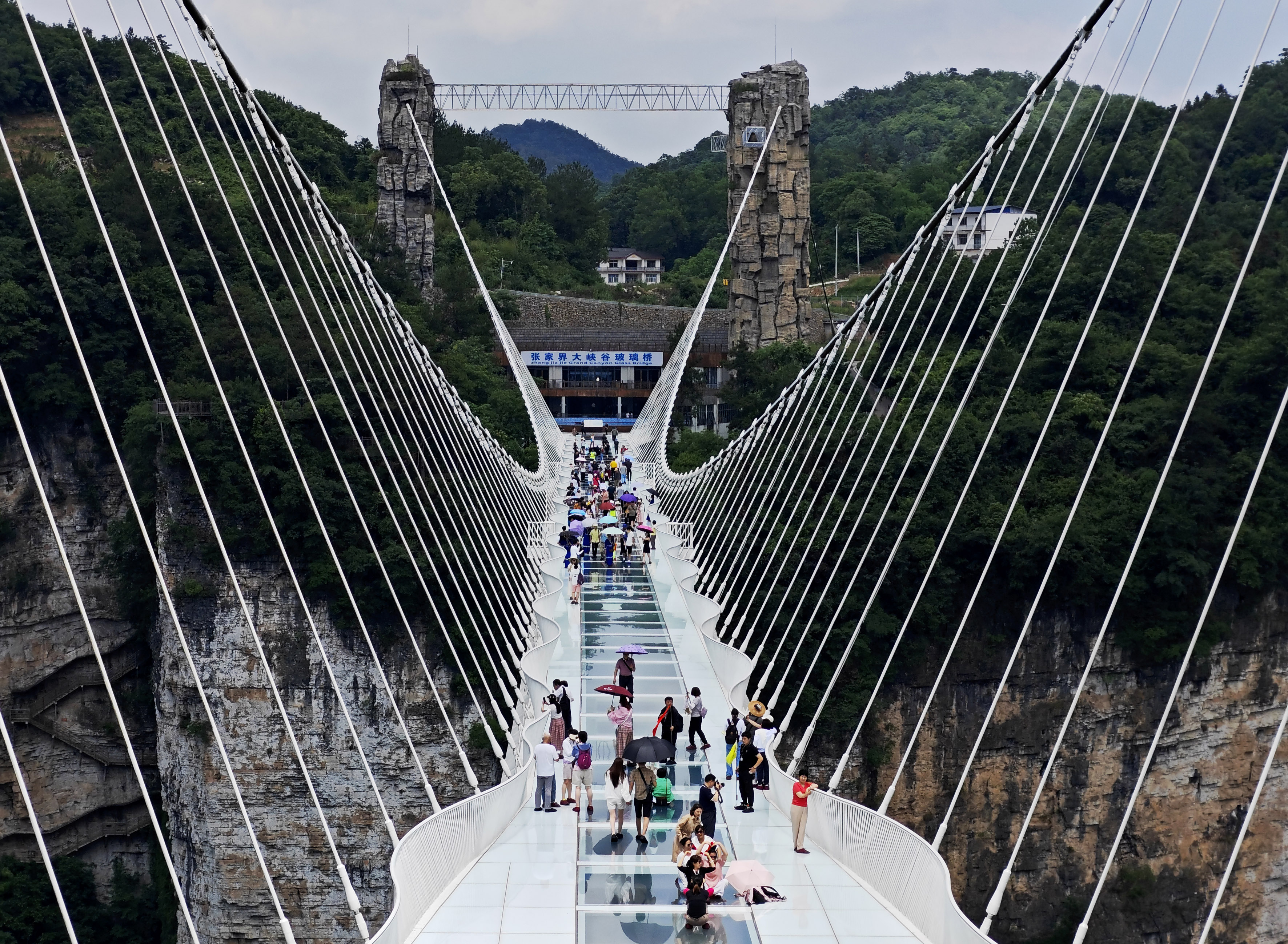 Visitors walk over the glass bridge at the Zhangjiajie National Forest Park, Zhangjiajie, Hunan Province. /CNSPHOTO