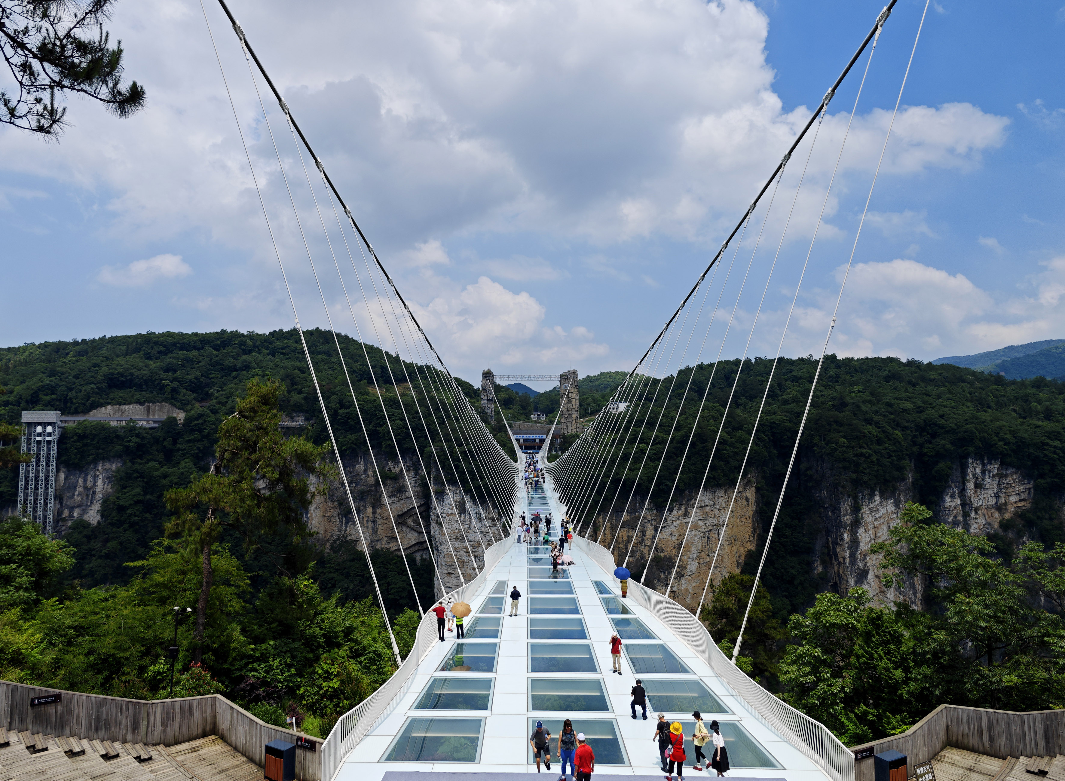Visitors walk over the glass bridge at the Zhangjiajie National Forest Park, Zhangjiajie, Hunan Province. /CNSPHOTO