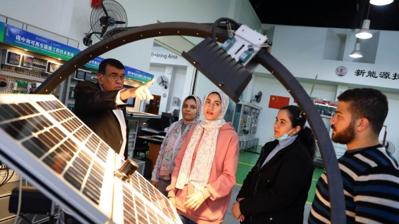 Professor Mohamad Ahmed Awad (1st L), director of Luban Workshop, introduces simulated wind-photovoltaic hybrid generating system to trainees at the workshop at Ain Shams University in Cairo, Egypt, on December 21, 2022. /Xinhua