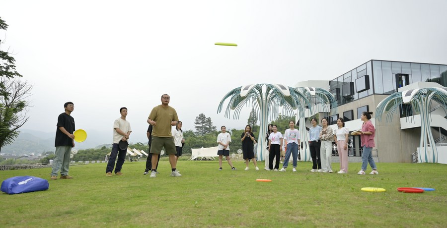 Young people play frisbee in front of a youth library in Yucun Village of Anji County, June 5, 2023. /Xinhua