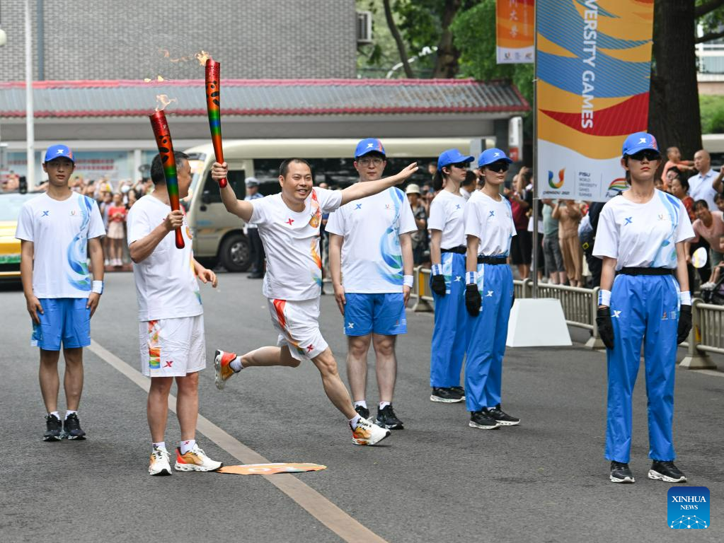 Torch bearer Liu Chuanjian (R) celebrates during the torch relay of the Chengdu 2021 FISU Summer World University Games at the Sichuan University in Chengdu, southwest China's Sichuan Province, July 2, 2023. /Xinhua