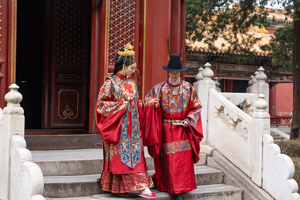 Two visitors wearing traditional Chinese wedding outfits are photographed at the Palace Museum in Beijing, March 17, 2023. It has been a trend to take wedding photographs inside the Forbidden City, and many related services can be found in the commercial photography market. /CFP