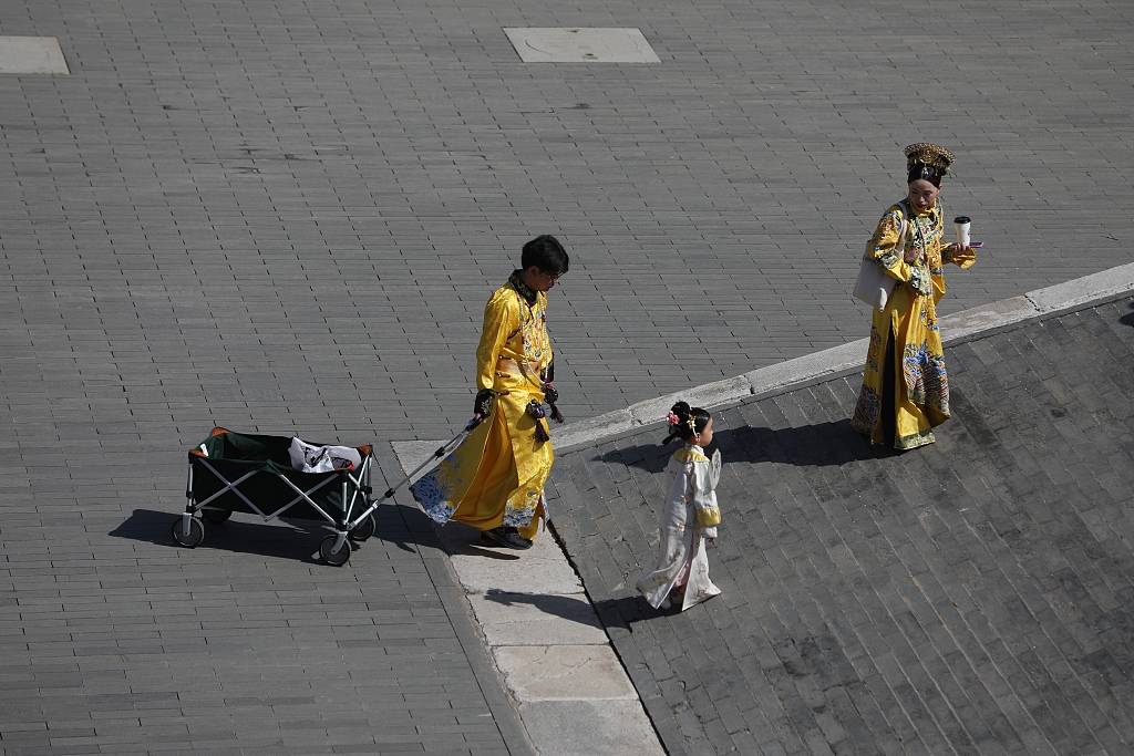 Dressed in traditional Chinese costume, a father lugs his family's belongings behind him in a cart at the Palace Museum in Beijing, April 29, 2023. /CFP