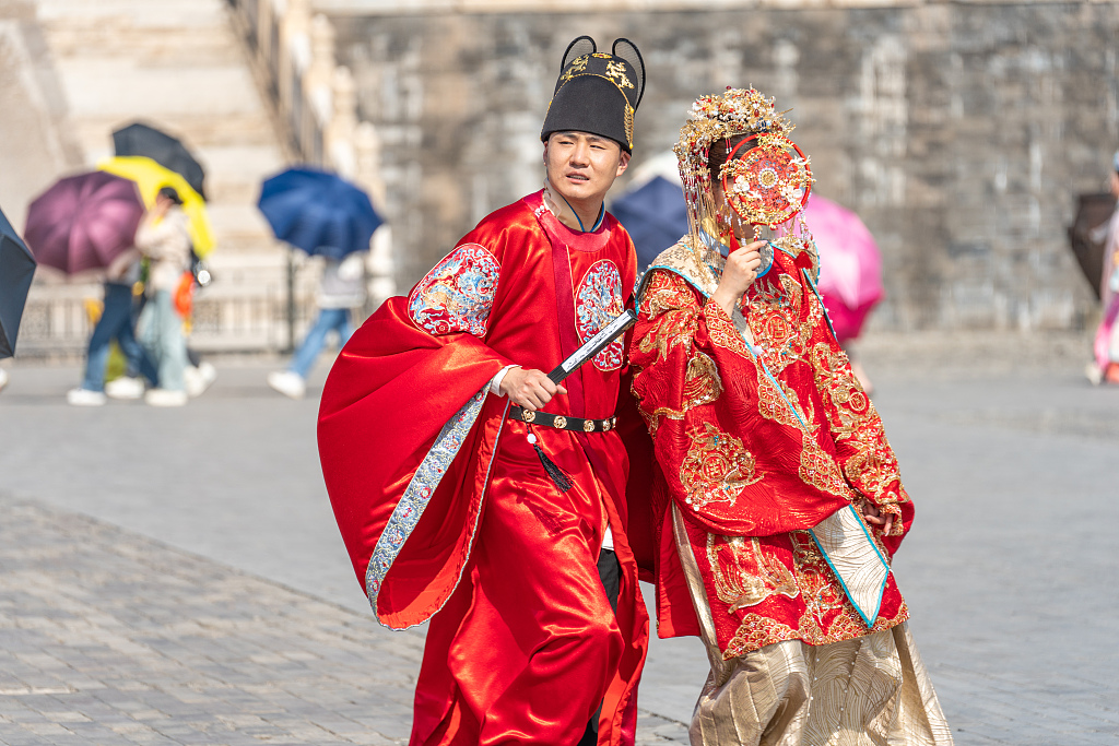 Visitors wearing traditional Chinese wedding outfits are photographed at the Palace Museum in Beijing, June 24, 2023. It has been a trend to take wedding photographs inside the Forbidden City, and many related services can be found in the commercial photography market. /CFP