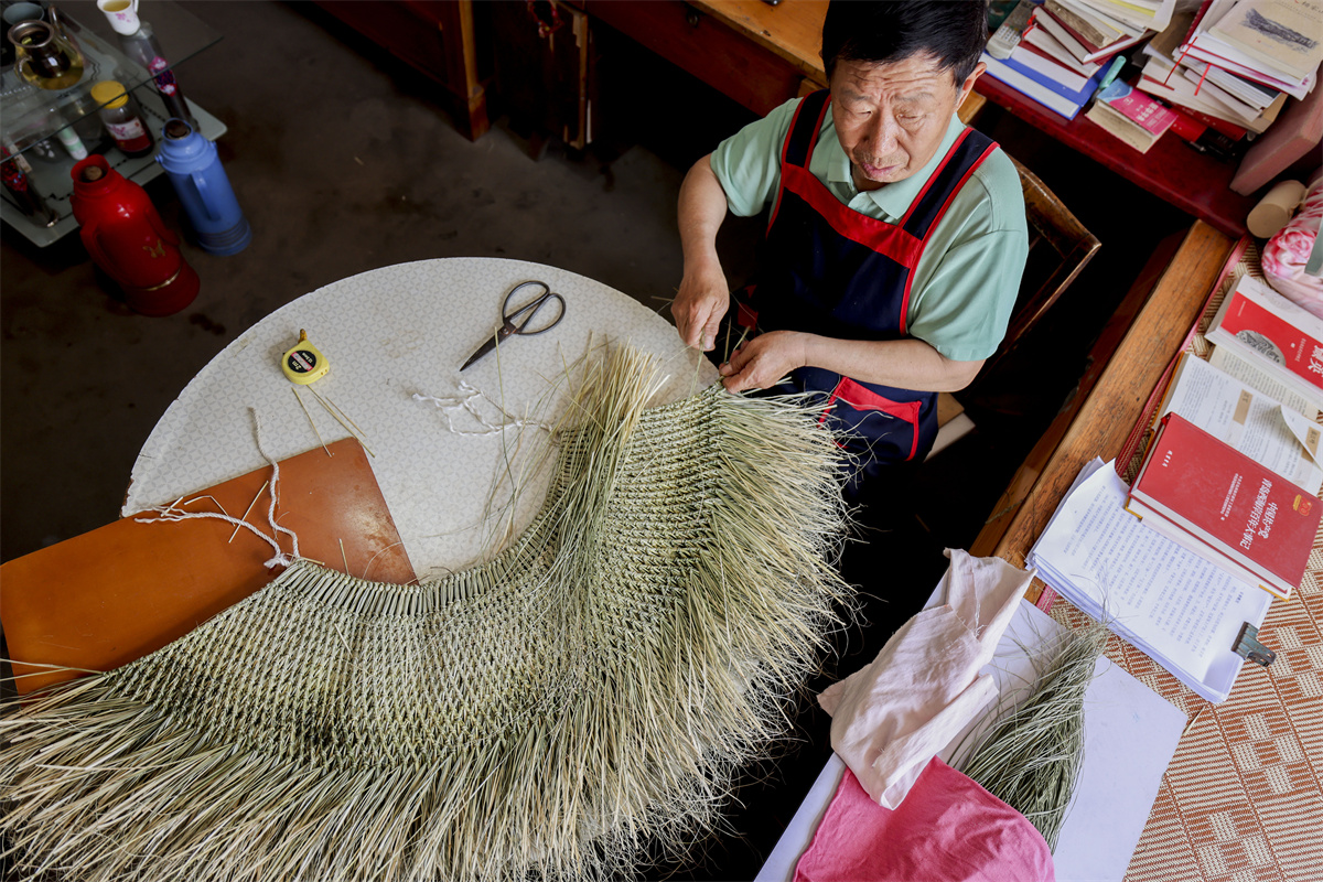 Zhao Wenzan weaves a straw rain cape on May 16, 2023, at Zhuangjiaying Village in Shandong Province. /CNSPHOTO