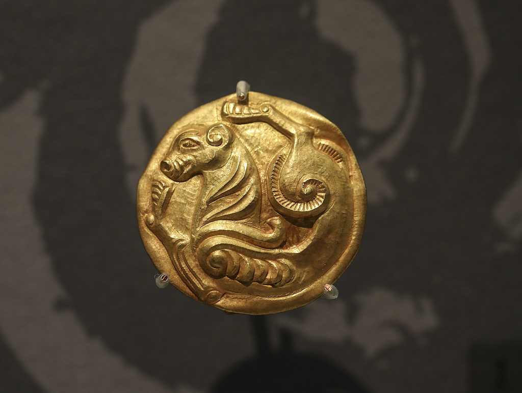 A thin, round golden decorative plate featuring an embossed tiger is displayed at a Xinjiang-themed exhibition at the National Museum in Beijing, June 21, 2023. /CFP