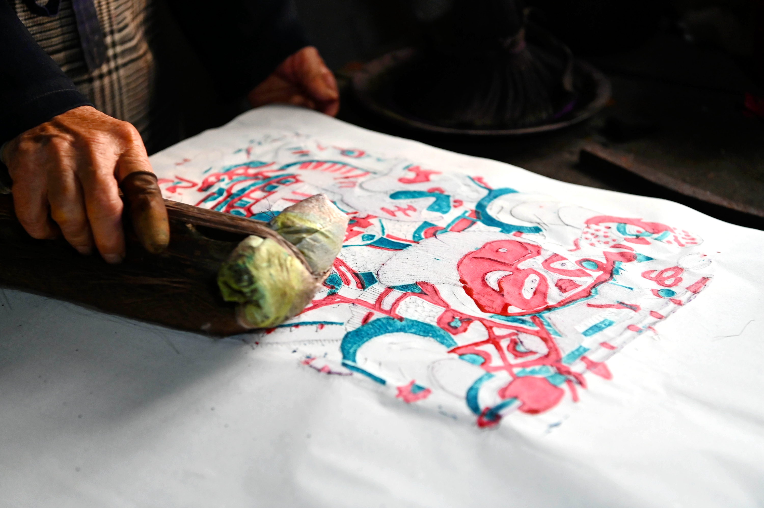 This photo taken on January 4, 2023 shows Rong Weichen, an inheritor of Dongchangfu New Year woodblock prints, checking prints in Liaocheng, Shandong Province. /CNSPHOTO