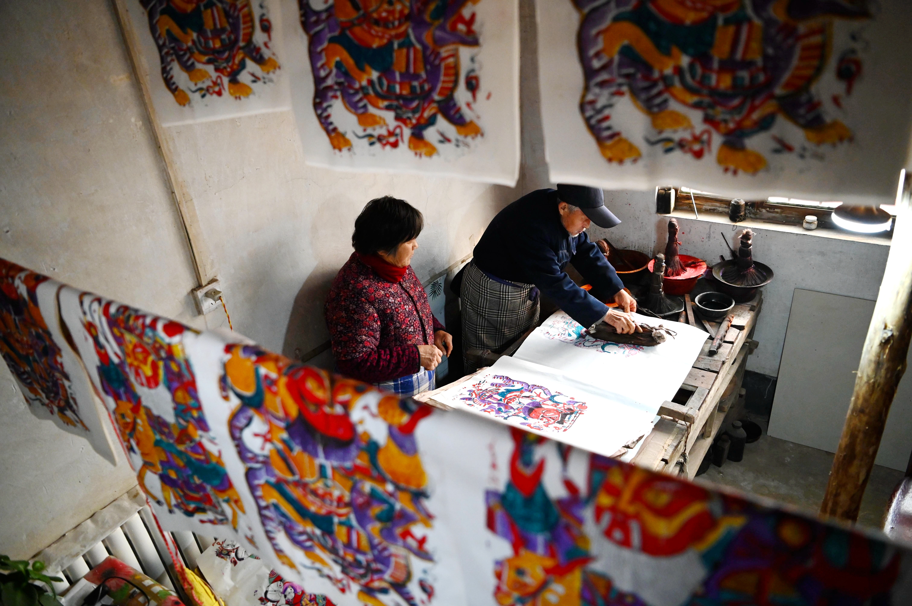 This photo taken on January 4, 2023 shows Rong Weichen, an inheritor of Dongchangfu New Year woodblock prints, checking prints in Liaocheng, Shandong Province. /CNSPHOTO