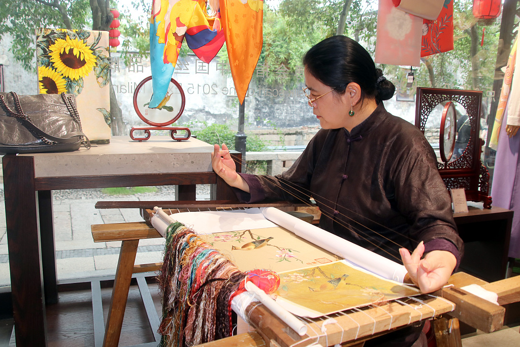 A woman shows Su embroidery skills at a shop in Pingjiang historic and cultural block in Suzhou, Jiangsu Province, July 7, 2023. /CFP