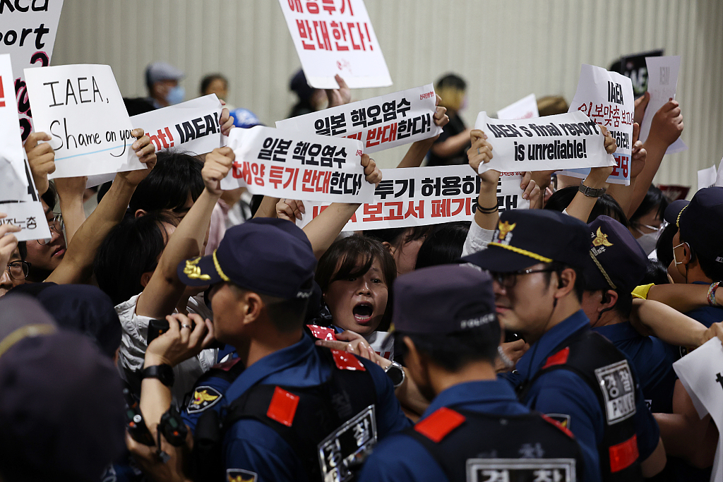 People hold signs protesting against the IAEA's report as Director General Rafael Grossi arrives in Seoul, South Korea, July 7, 2023. /CFP