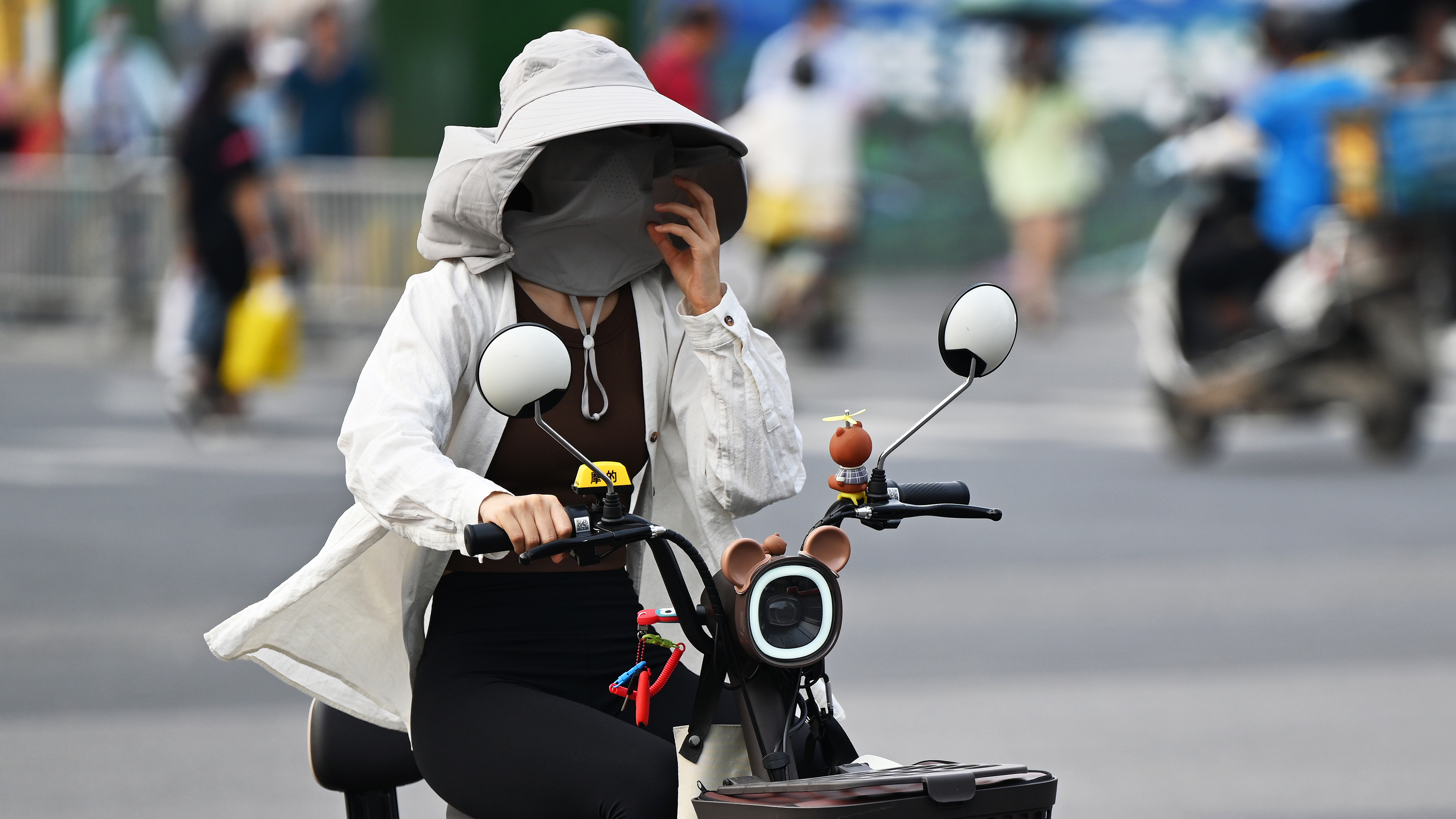 A woman wearing sun protection clothing rides an electric bike during the hot weather in Chengdu, southwest China's Sichuan Province, May 30, 2023. /CFP