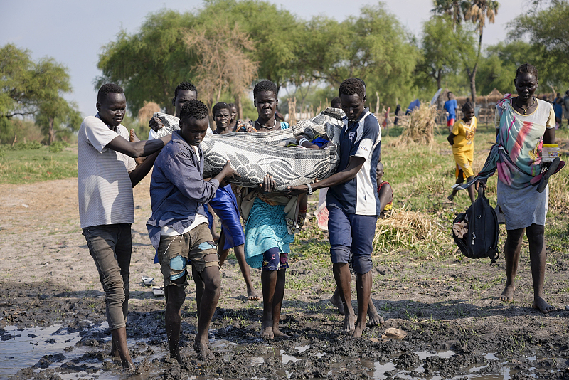 Villagers use a mat to carry a sick woman to a boat operated by the International Medical Corps to take her to a nearby town, Canal-Pigi county, South Sudan, May 7, 2023. /CFP
