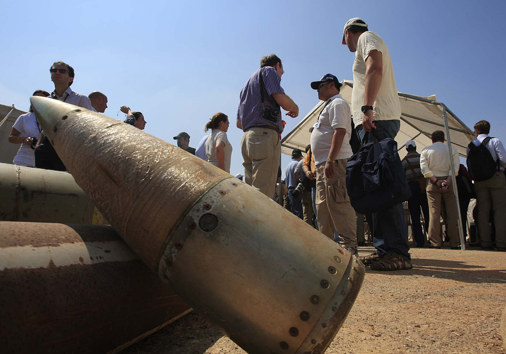 Activists and international delegations stand next to cluster bomb units during a visit to a Lebanese military base at the opening of the Second Meeting of States Parties to the Convention on Cluster Munitions in the southern town of Nabatiyeh, Lebanon, September 12, 2011. /CFP