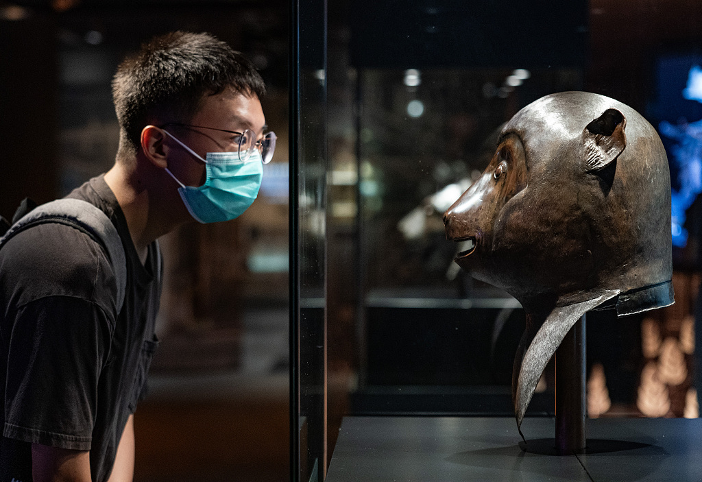 A visitor stares at the bronze monkey head sculpture, a treasure of Beijing's Old Summer Palace, on display at the City University of Hong Kong, July 4, 2023. /CFP