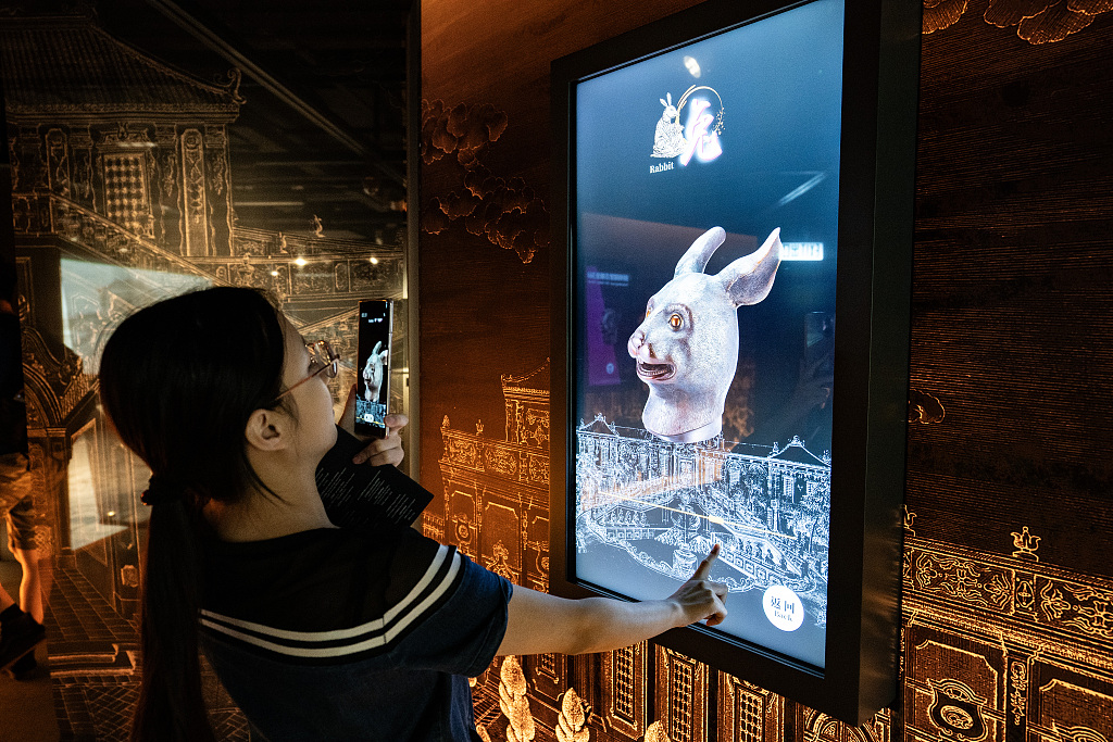 A visitor takes a photo while appreciating the digital version of the bronze rabbit head sculpture, a treasure of Beijing's Old Summer Palace, at the City University of Hong Kong, July 4, 2023. /CFP