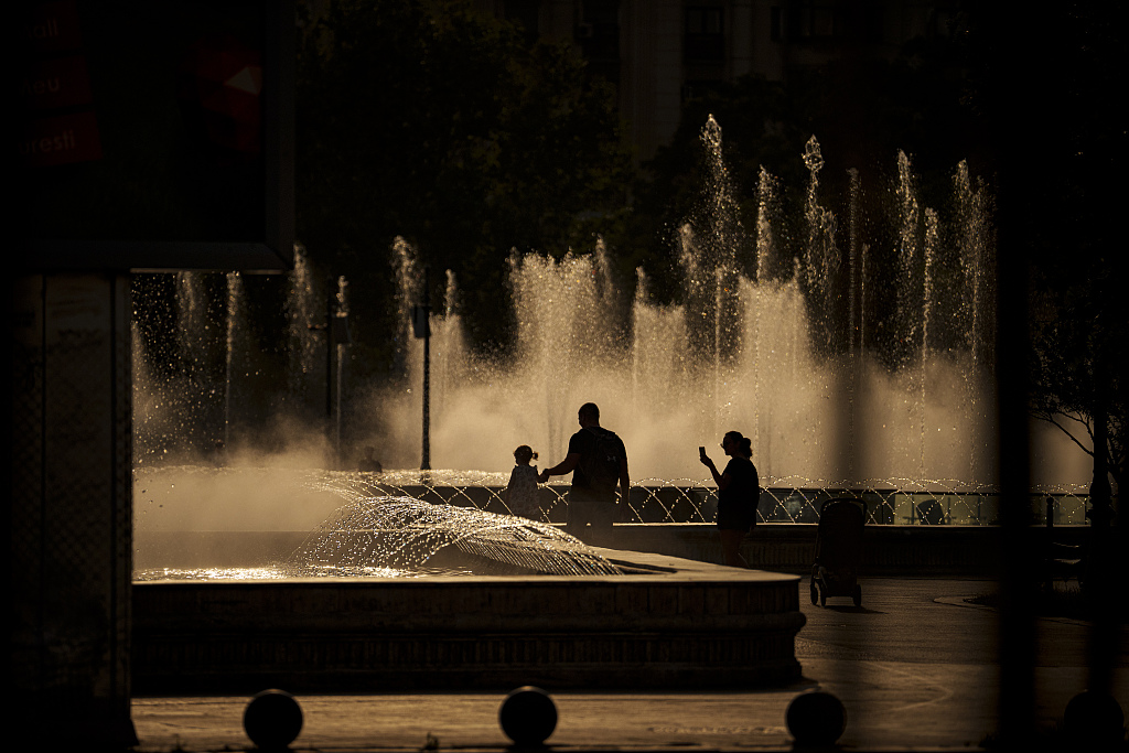 A family walks by a public fountain in Bucharest, Romania, July 13, 2023. /CFP