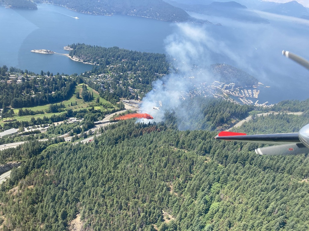 这张照片显示了2023年6月26日，一架消防飞机在加拿大不列颠哥伦比亚省西温哥华附近马蹄湾以东的怀特湖野火上投放阻燃剂。/法新社