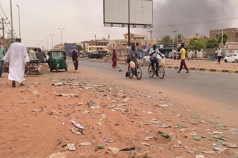 Smoke rises above buildings as people walk along a street in Omdurman, Sudan, July 15, 2023. /CFP